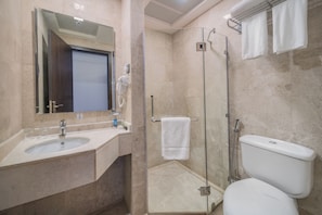 A modern bathroom with a glass-enclosed shower, a sink with a mirror, and a toilet.