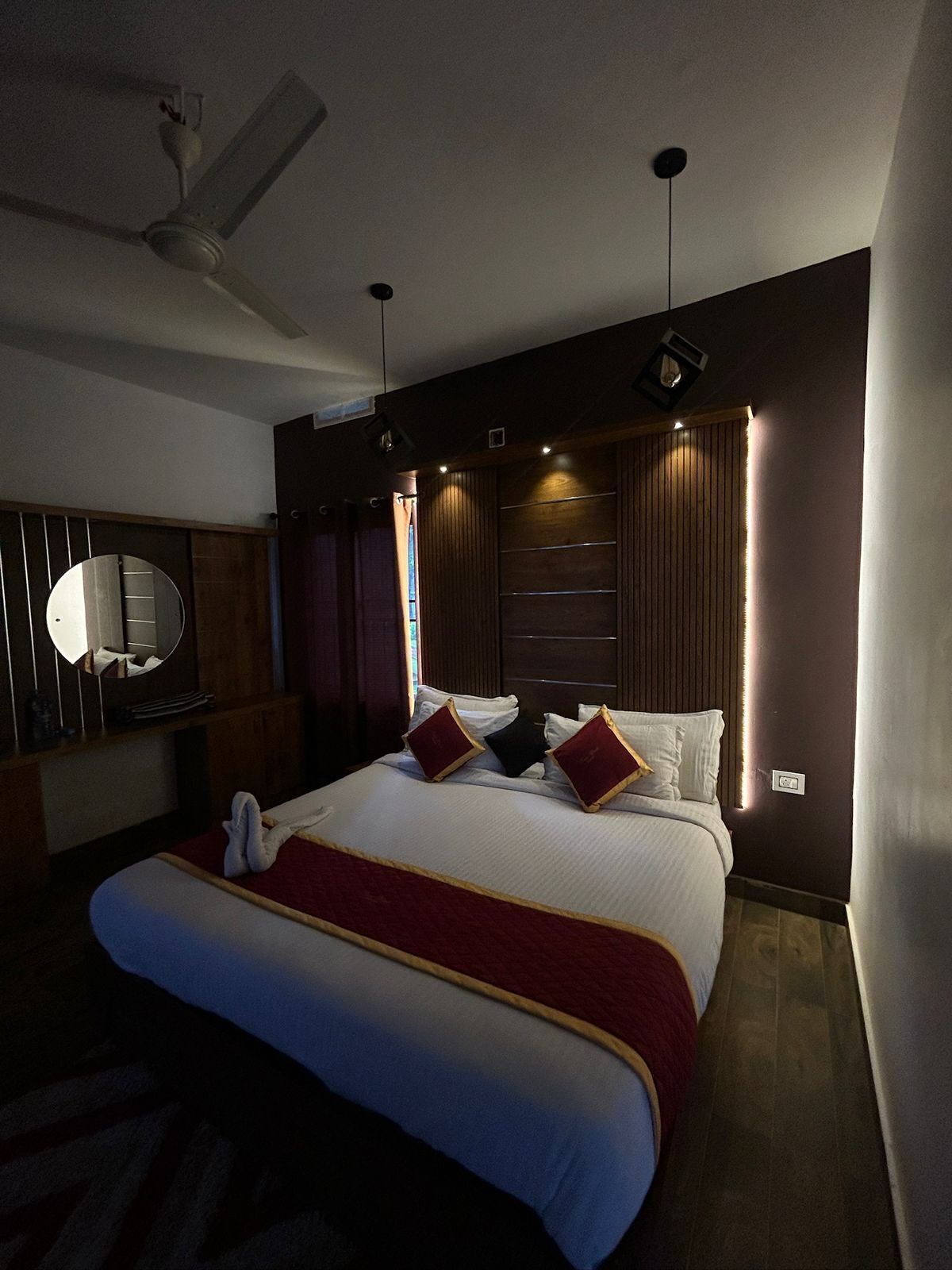 Ein modernes Hotelzimmer mit einem großen Bett, einem Deckenventilator und einem an der Wand befestigten Fernseher.