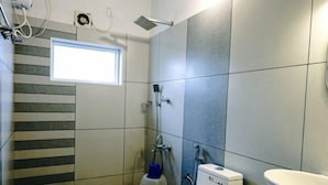 Une salle de bain équipée de toilettes, d’un lavabo, d’une douche et d’une fenêtre.