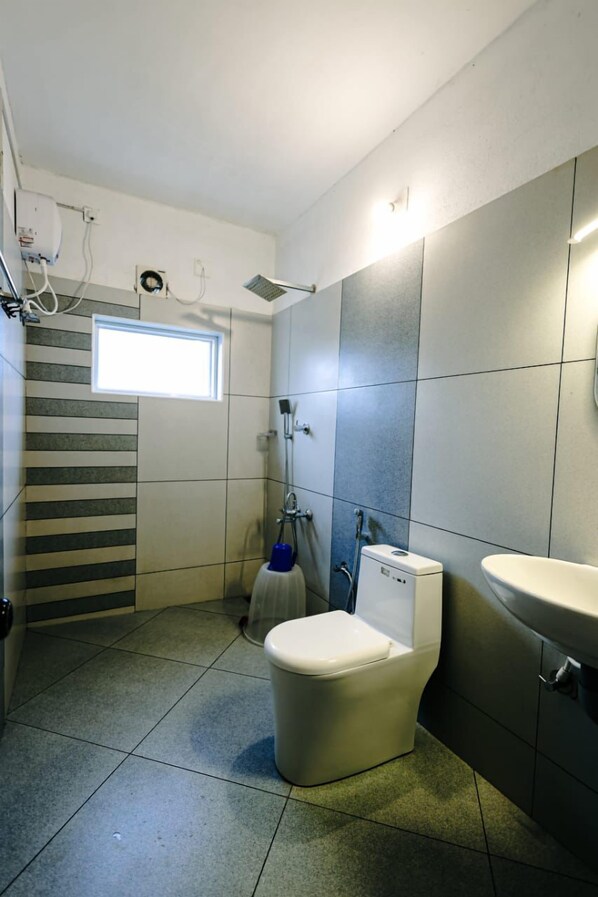 Un baño con inodoro, lavamanos, ducha y ventana.