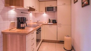 A compact kitchen with a wooden island, white cabinets, a microwave, and a trash bin. - Liebevoll Eingerichtetes Appartement (Rechlin)