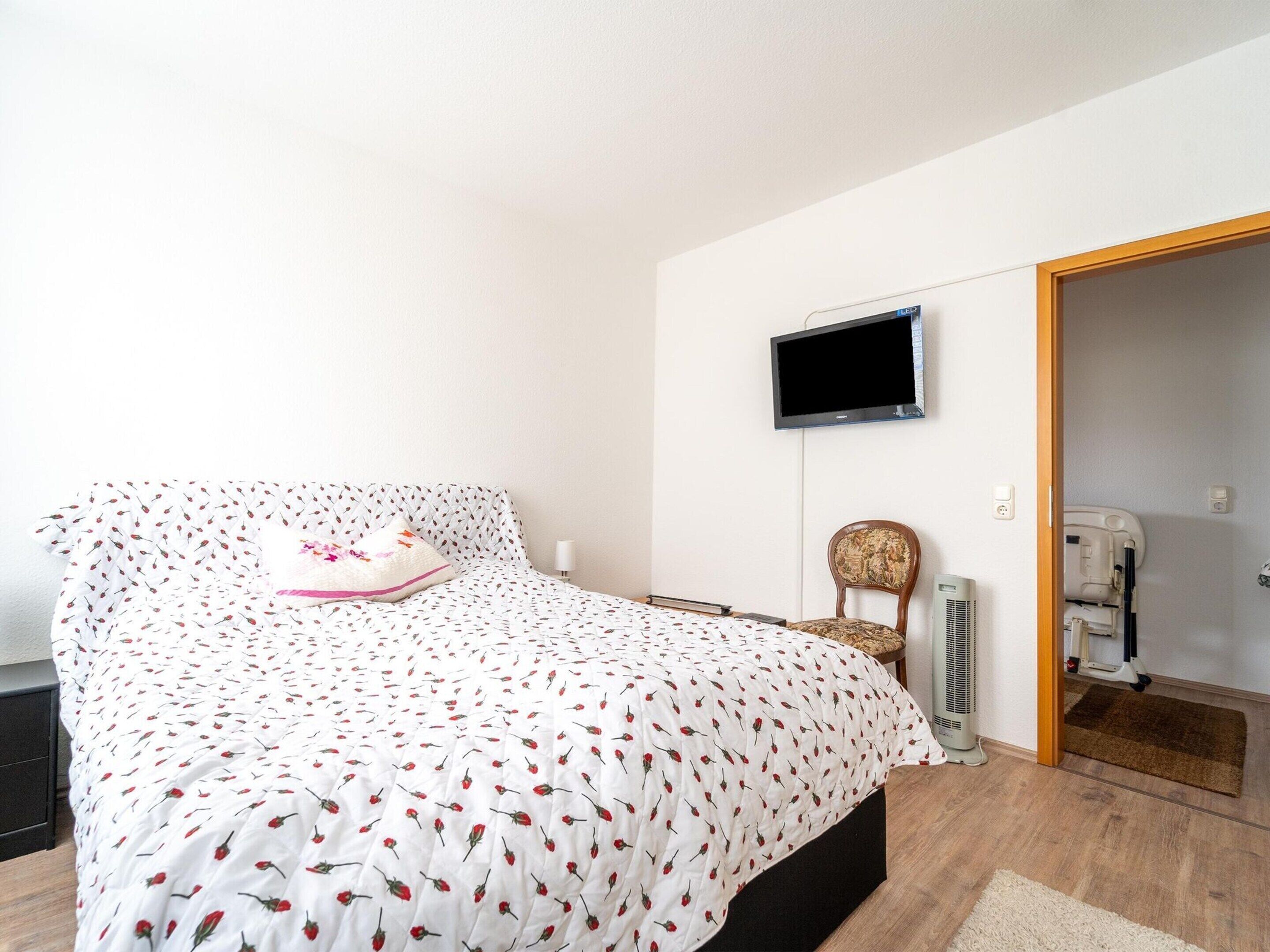 Une chambre avec un lit, une chaise, une télévision et un radiateur.