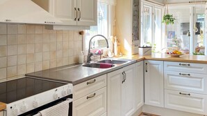 Una cocina con armarios blancos, una estufa negra y un ventanal con vistas al exterior.