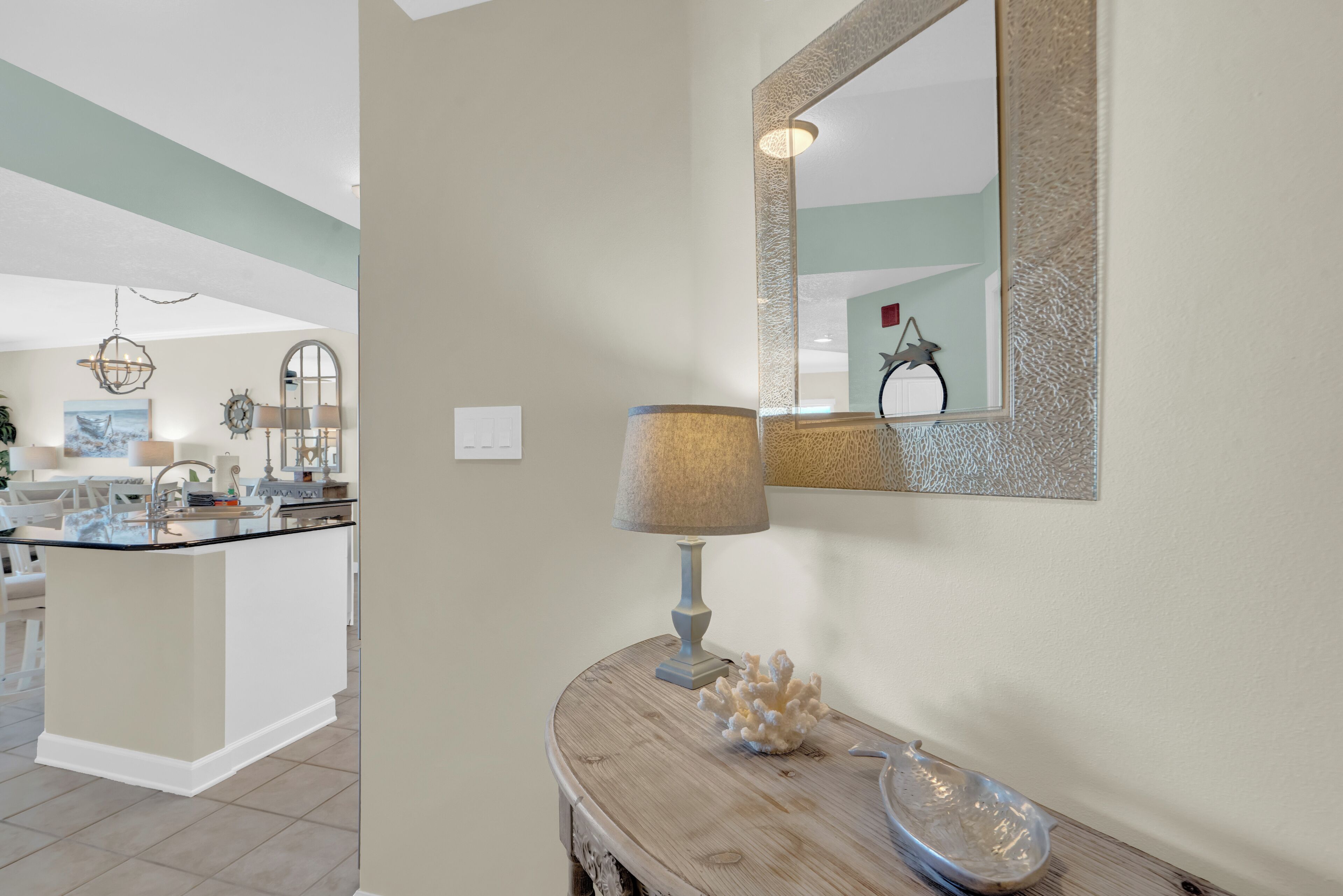 A kitchen with a central island, a wooden console table with a lamp, and a decorative mirror.
