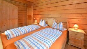 Een houten kamer met twee bedden, een kledingkast en bedlampjes.