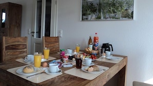 Ein Frühstückstisch ist gedeckt mit Tellern, Tassen und verschiedenen Frühstücksartikeln.