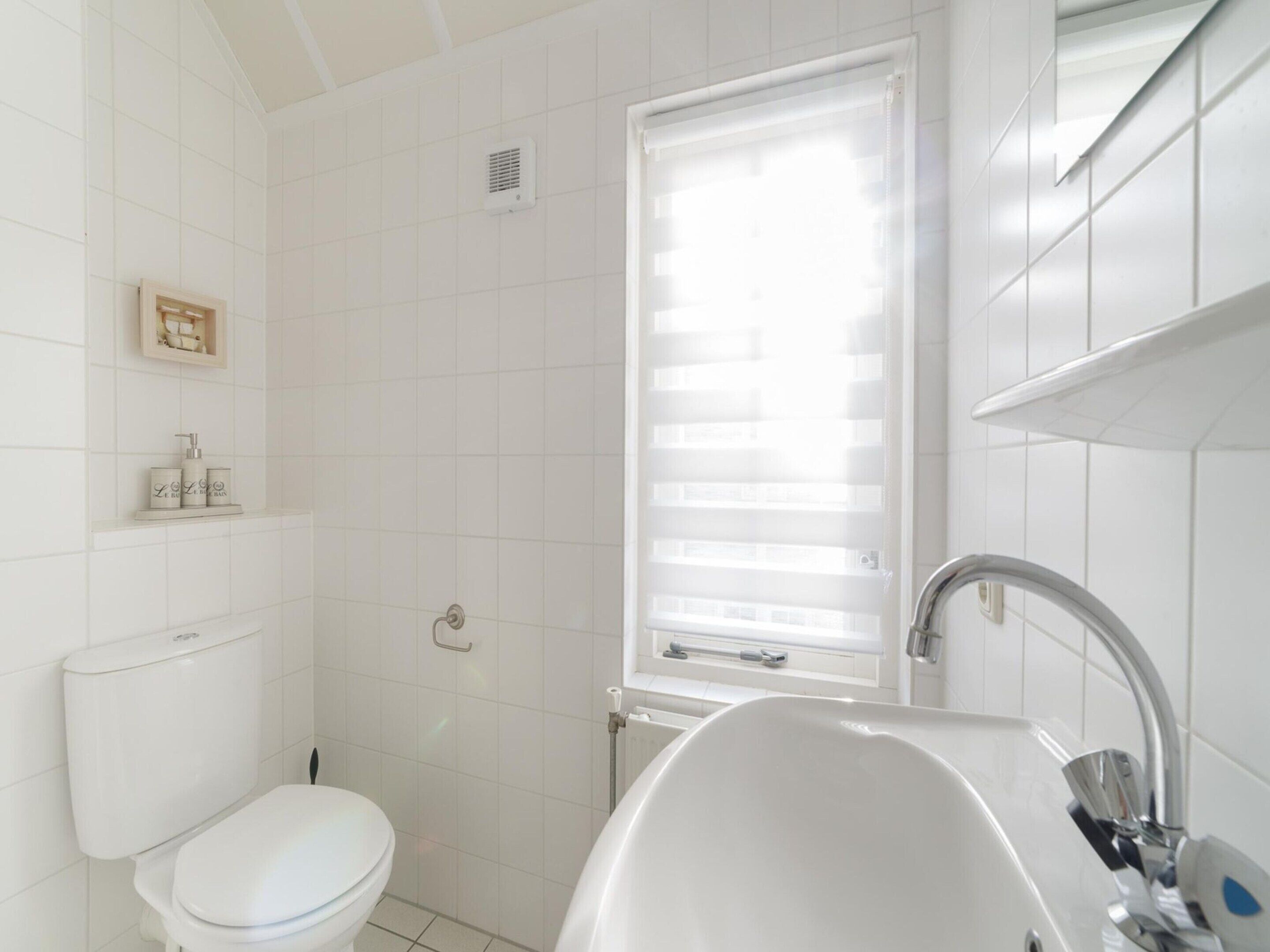 Et badeværelse med toilet, brusebad og håndvask.