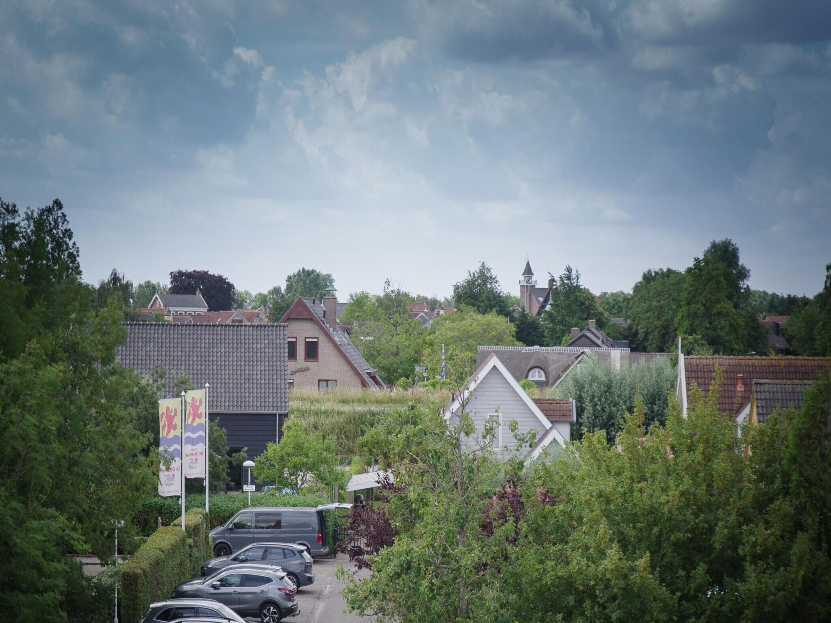 A residential area with houses, parked cars, and a church in the background.
