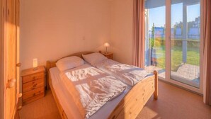 A bedroom with a bed, bedside tables, a lamp, and a large window with a view of the outdoors. - Liebevoll Eingerichtetes Appartement (Rechlin)