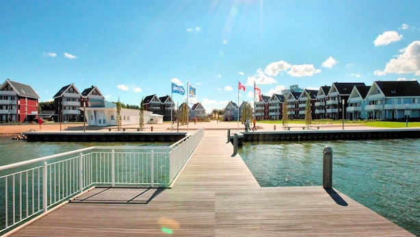 A waterfront property with a wooden dock, a marina, and multiple buildings with balconies. - Liebevoll Eingerichtetes Appartement (Rechlin)