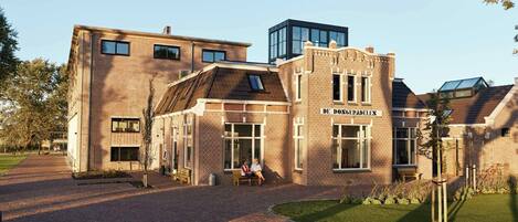 A modern building with a brick facade and a sign reading "DE DONGERADELEN".