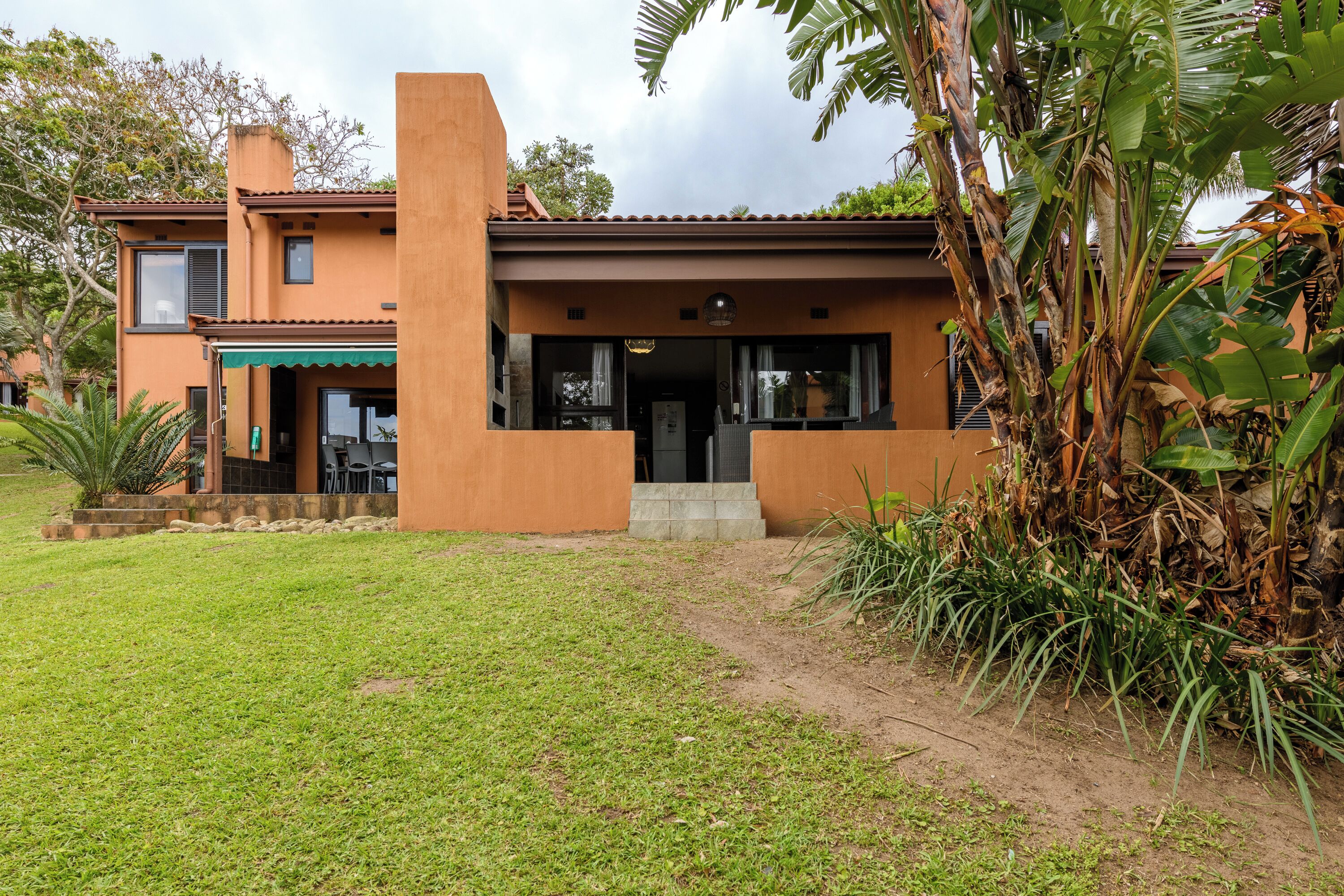 A two-story house with a front entrance, a small porch, and a garden area.