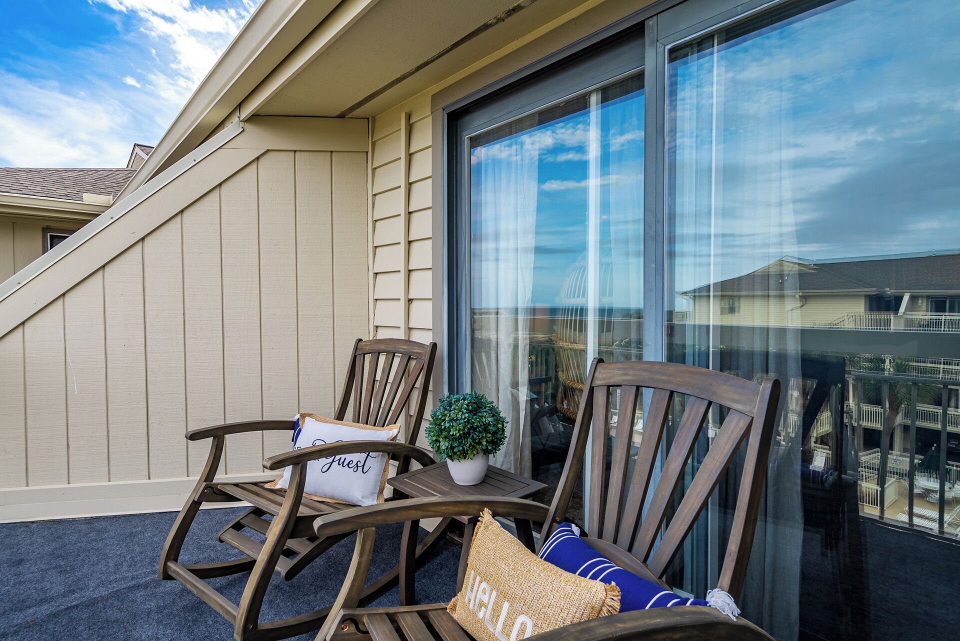 A balcony with two wooden rocking chairs, a small table, and a potted plant.