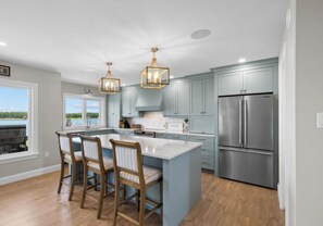 A modern kitchen with a large island, stainless steel appliances, and a view of the outdoors.