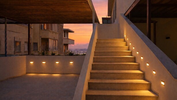 Eine Treppe mit beleuchteten Geländern, die zu einem Gebäude mit Sonnenuntergangsblick führt.