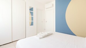 Ein Schlafzimmer mit einem Bett, einem Kleiderschrank und einer Wand mit geometrischem Muster.