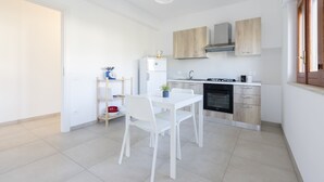 Eine moderne Küche mit weißen Schränken, einem Esstisch mit Stühlen und einem eingebauten Backofen.