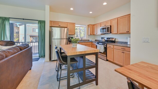 A modern kitchen with wooden cabinets, a stainless steel refrigerator, a microwave, and a dining area with a table and chairs. - 2 Mi to Dtwn Flagstaff: Home w/ Balcony! (Flagstaff)