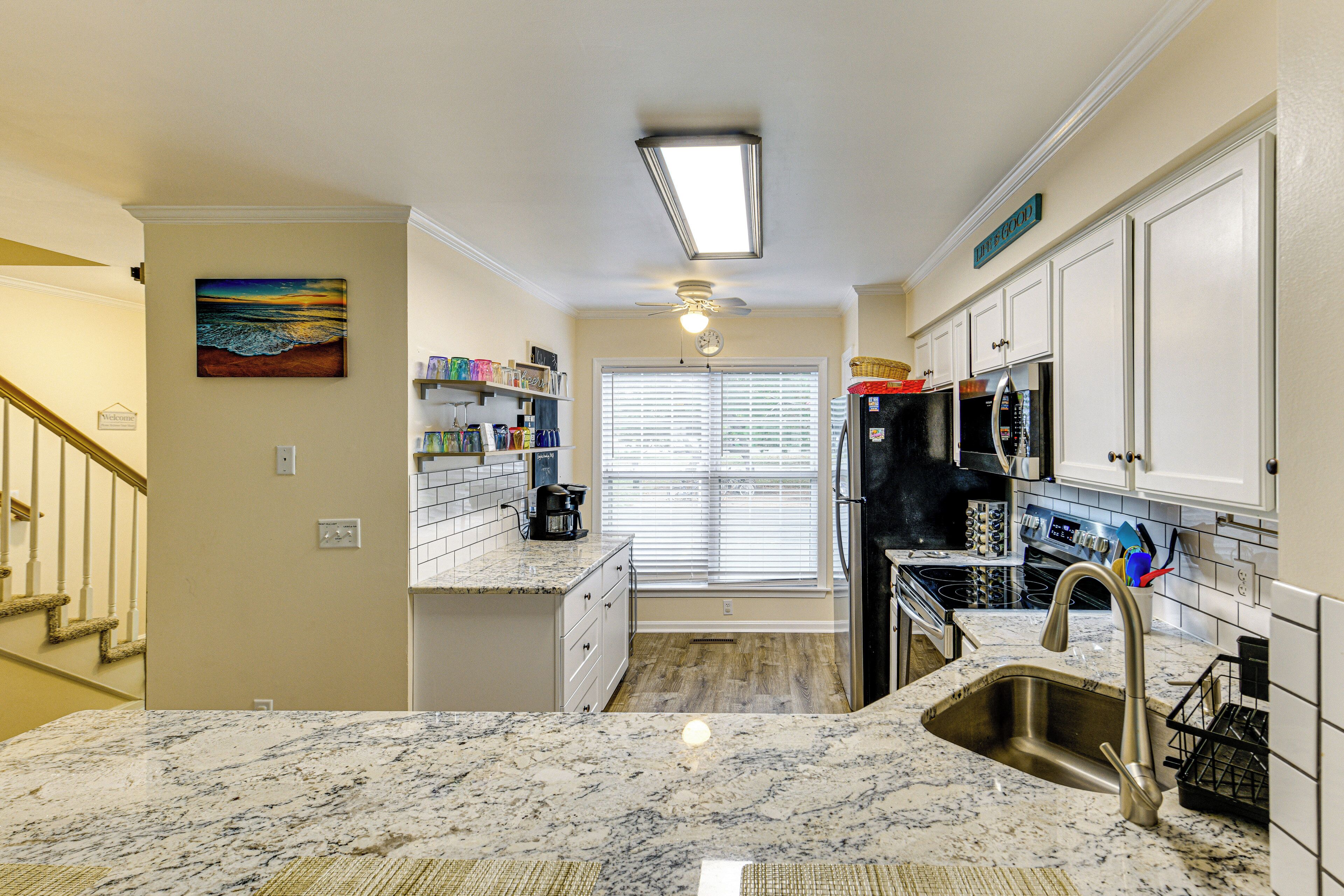 A kitchen with a marble countertop, stainless steel appliances, and a view to the outside.