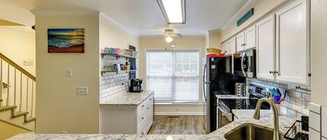 A kitchen with a marble countertop, stainless steel appliances, and a view to the outside.