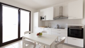 Une cuisine moderne avec des meubles blancs, un four à micro-ondes, une cuisinière et un coin repas comprenant une table et des chaises.