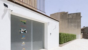 Un bâtiment à la façade blanche, doté d’un grand portail de garage et d’une structure en béton située sur la droite.