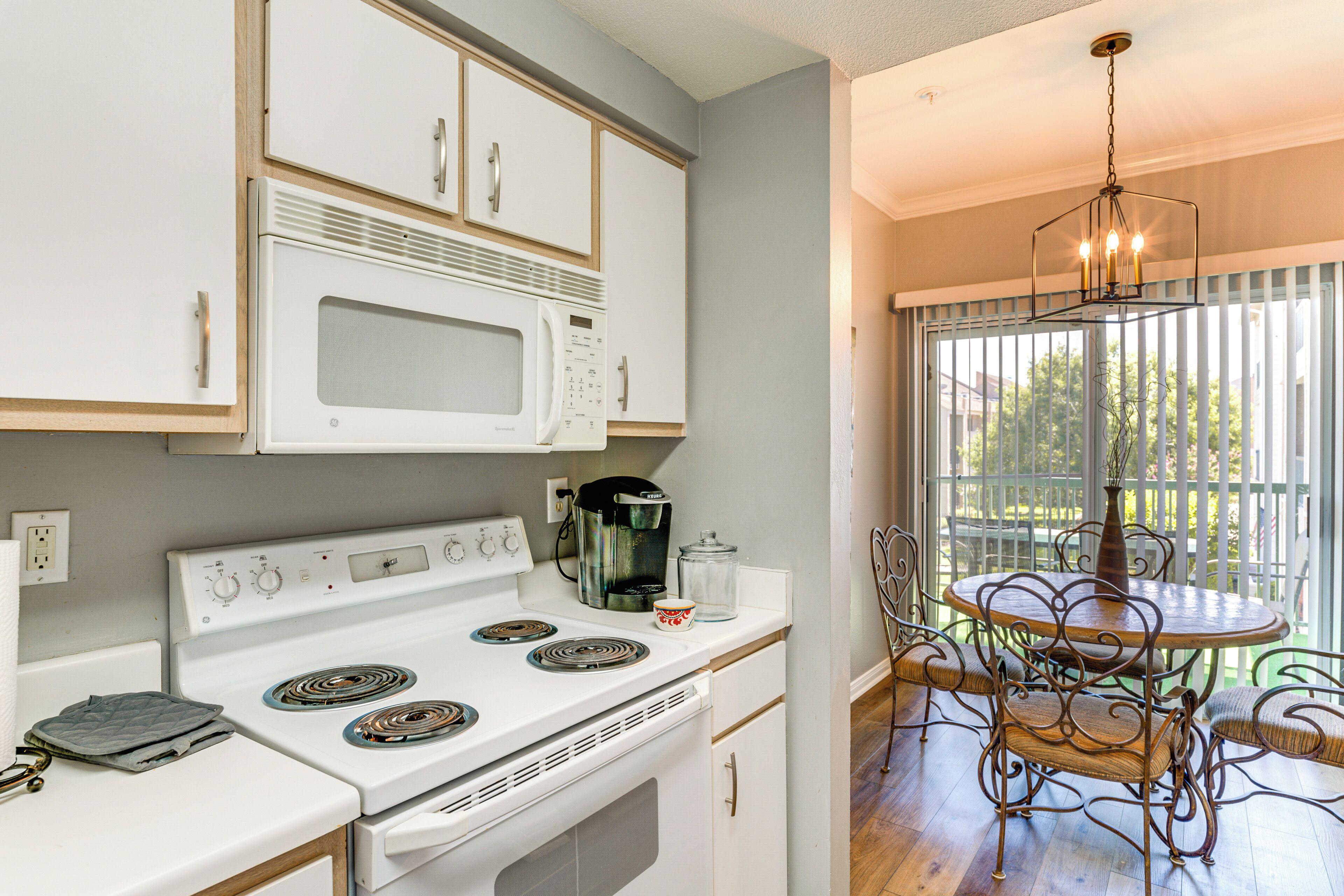 A kitchen with white cabinets, a stove, and a dining area with a table and chairs.