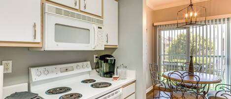 A kitchen with white cabinets, a stove, and a dining area with a table and chairs.