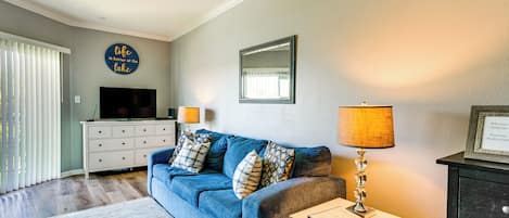 A living room with a blue sofa, a TV, a lamp, and a framed picture on the wall.