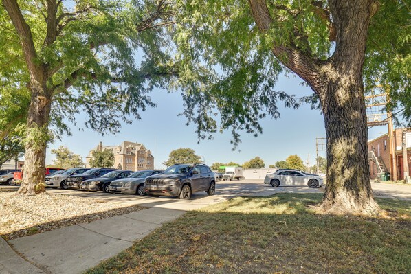 A parking lot with several cars parked under trees. - Yankton Apt: 1 Mi to Mount Marty University! (Yankton)