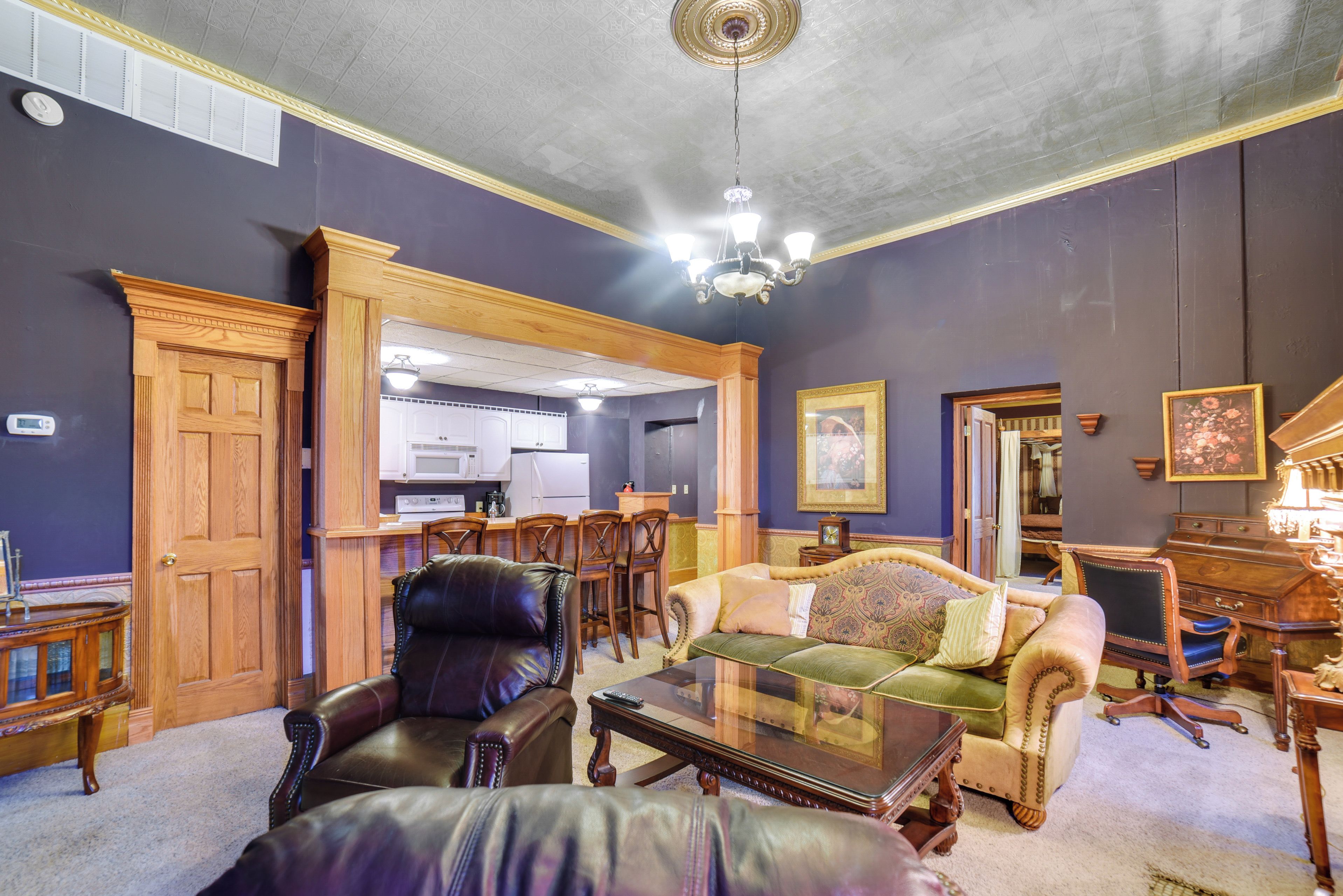 A spacious living room with a fireplace, leather armchairs, a sofa, and a dining area with wooden chairs and a table.