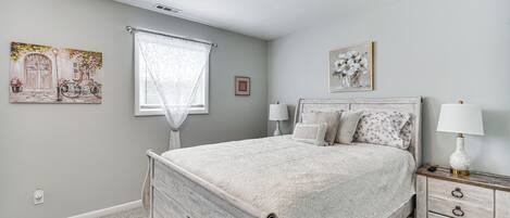 Un dormitorio con cama, mesita de noche y dos lámparas de pared.