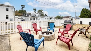 A backyard with Adirondack chairs, a fire pit, and a grill. - 2 Blocks to Beach: Apt w/ Grill in Ocean Gate! (Ocean Gate)