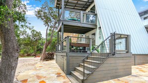 A two-story building with a stone-paved entrance and a staircase leading to a balcony.