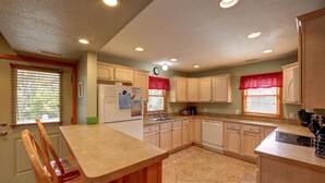 A kitchen with wooden cabinets, a refrigerator, a sink, and a stove. - Diamond In The Rough: Rooftop Deck | Rec Room (Ocracoke)