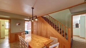 A dining area with a wooden table and chairs, a staircase, and a ceiling fan. - Diamond In The Rough: Rooftop Deck | Rec Room (Ocracoke)