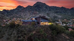 Une maison moderne dotée d’un grand patio, entourée d’un paysage montagneux.