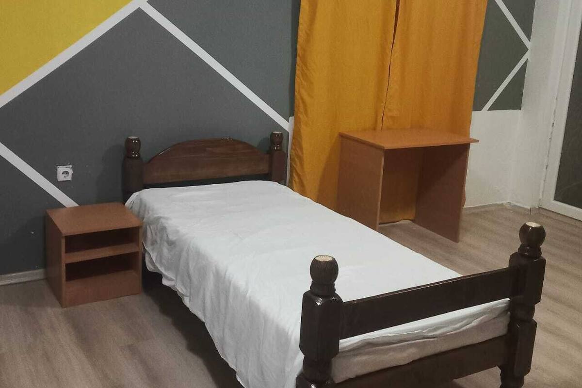 Ein Zimmer mit einem Bett, einem Nachttisch und einem Holzschrank.