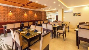 A restaurant with brick walls, multiple tables with chairs, and recessed lighting. - Signature inn Mcleodganj (Dharamshala)