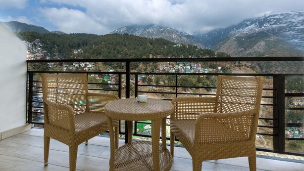 A balcony with wicker furniture and a view of mountains. - Signature inn Mcleodganj (Dharamshala)
