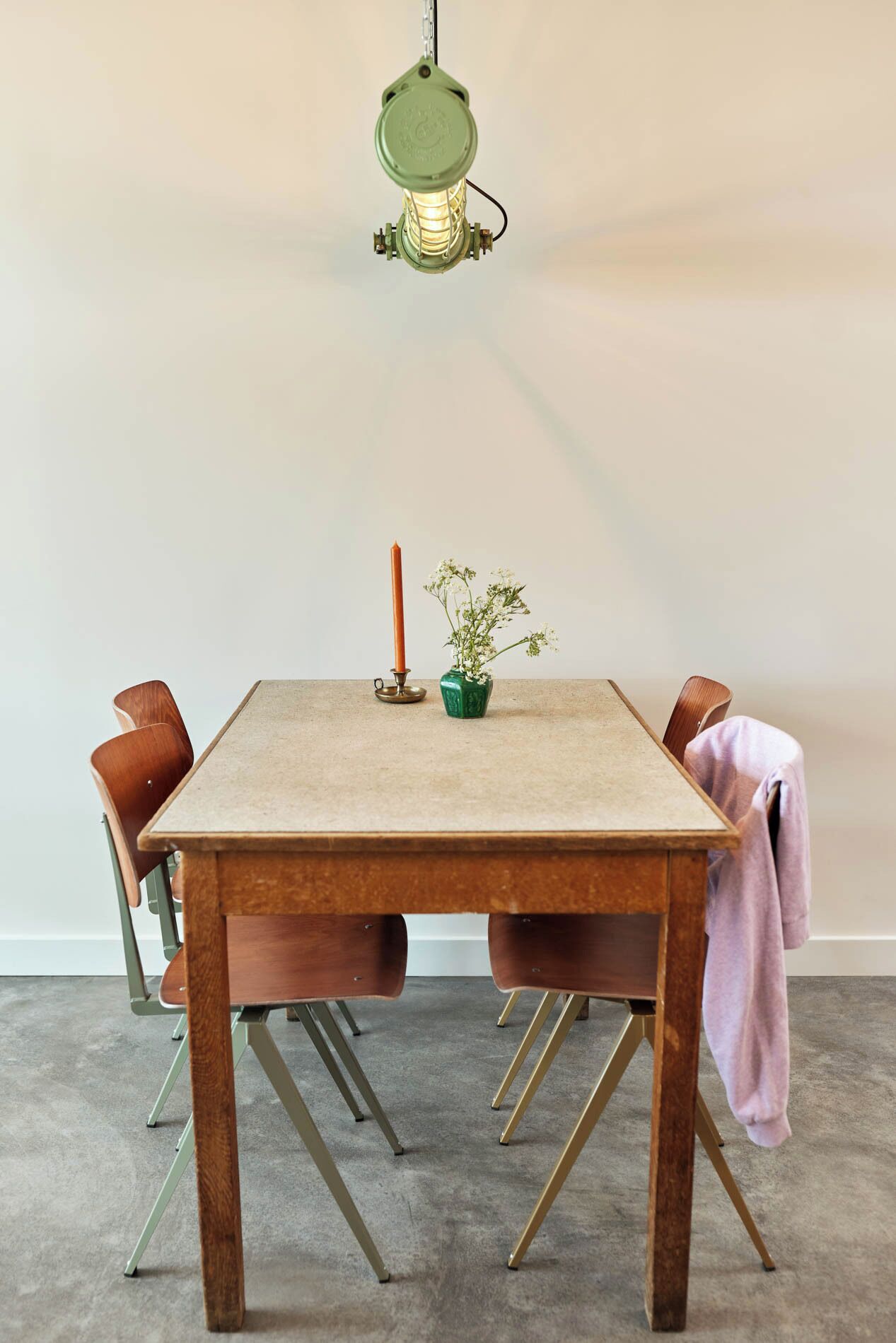 Una mesa de comedor con una vela y una planta pequeña, rodeada de sillas.