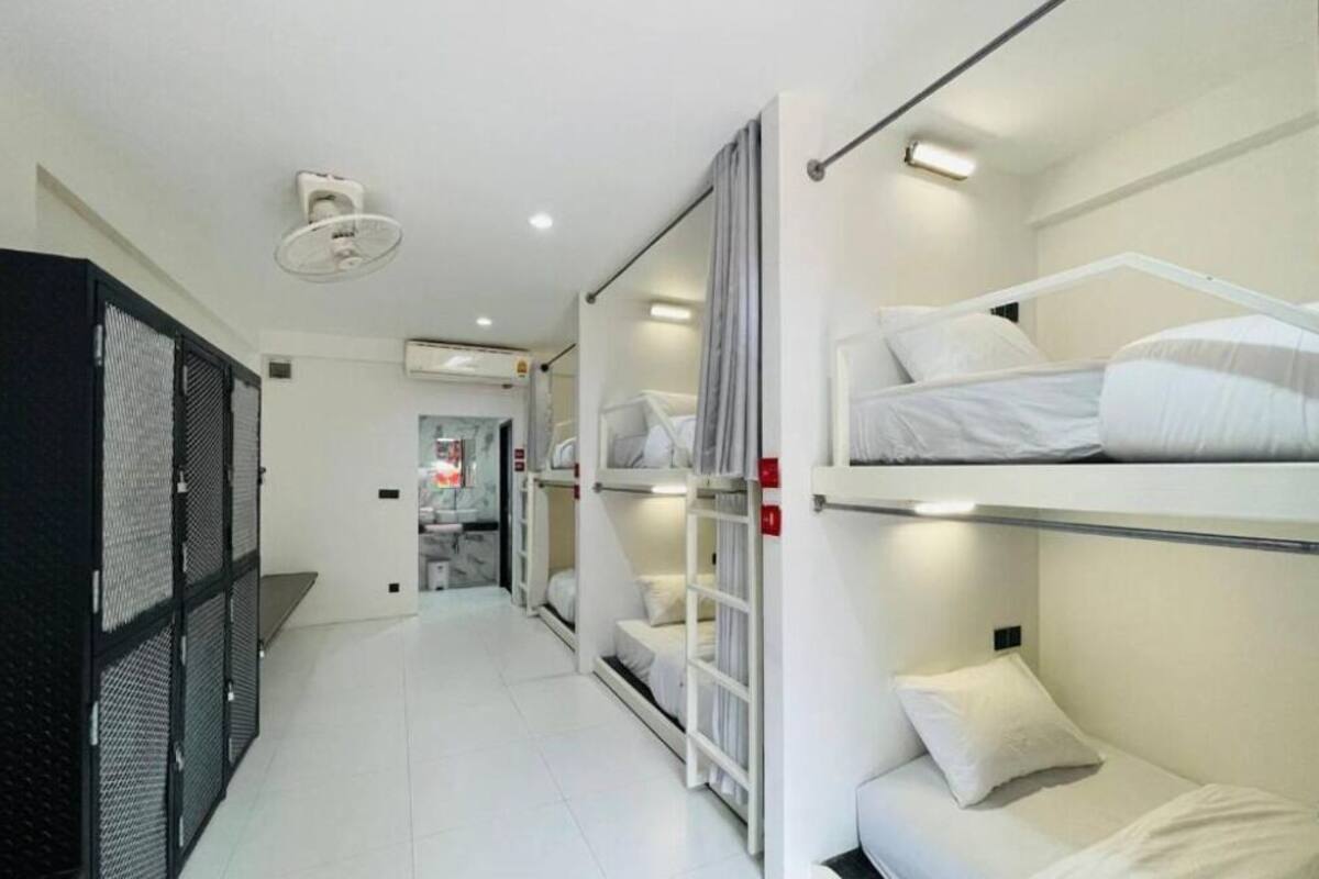 A hotel room with bunk beds, a small desk, and a wardrobe.