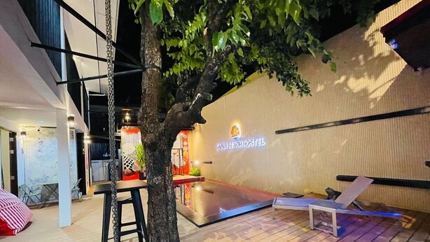 A modern hostel with a wooden deck, a tree, and a sign reading "Samuibeach Hostel". - Samui Beach Hostel (Koh Samui)