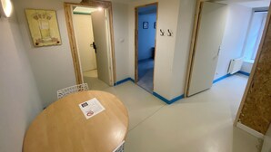 Quarto com mesa redonda, porta para outro cômodo e placa na parede.