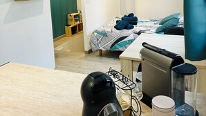 Ein Hotelzimmer mit Bett, Schreibtisch mit Kaffeemaschine, Wandfernseher und Fenster mit Außenblick.