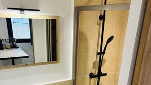 Ein modernes Badezimmer mit einem weißen Waschbecken, einem Holz-Waschtisch, einem großen Spiegel und einer Duschkabine.