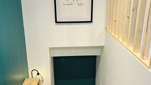 Ein Flur mit einem gerahmten Kunstwerk, einem Holzschrank mit einer Leuchte und einer dunklen Tür.