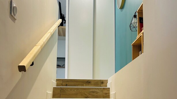 Eine Holztreppe mit weißen Wänden und einer blauen Akzentwand.