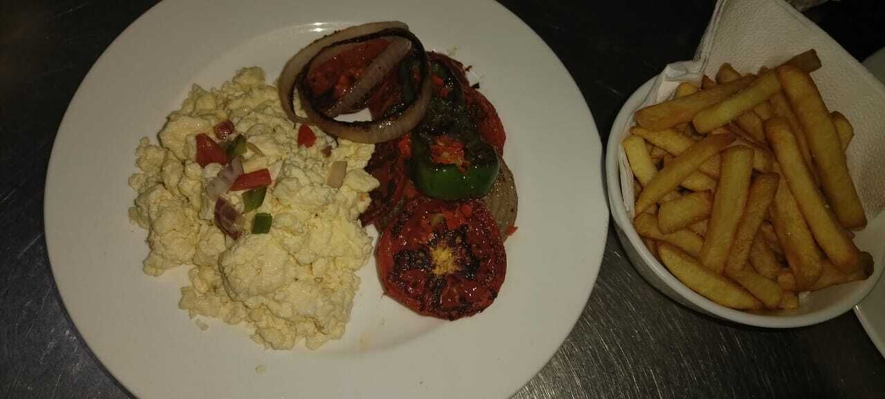 Un plat amb ous barrejats, una llesca de tomàquet amb pebrot i una ració de patates fregides.