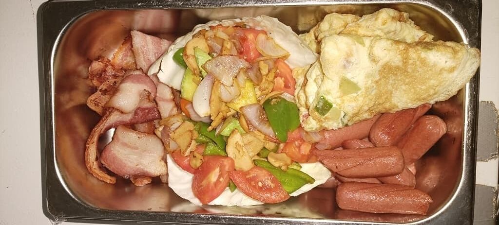 Un plateau-repas comprenant du bacon, des saucisses, une tortilla aux légumes et une omelette.